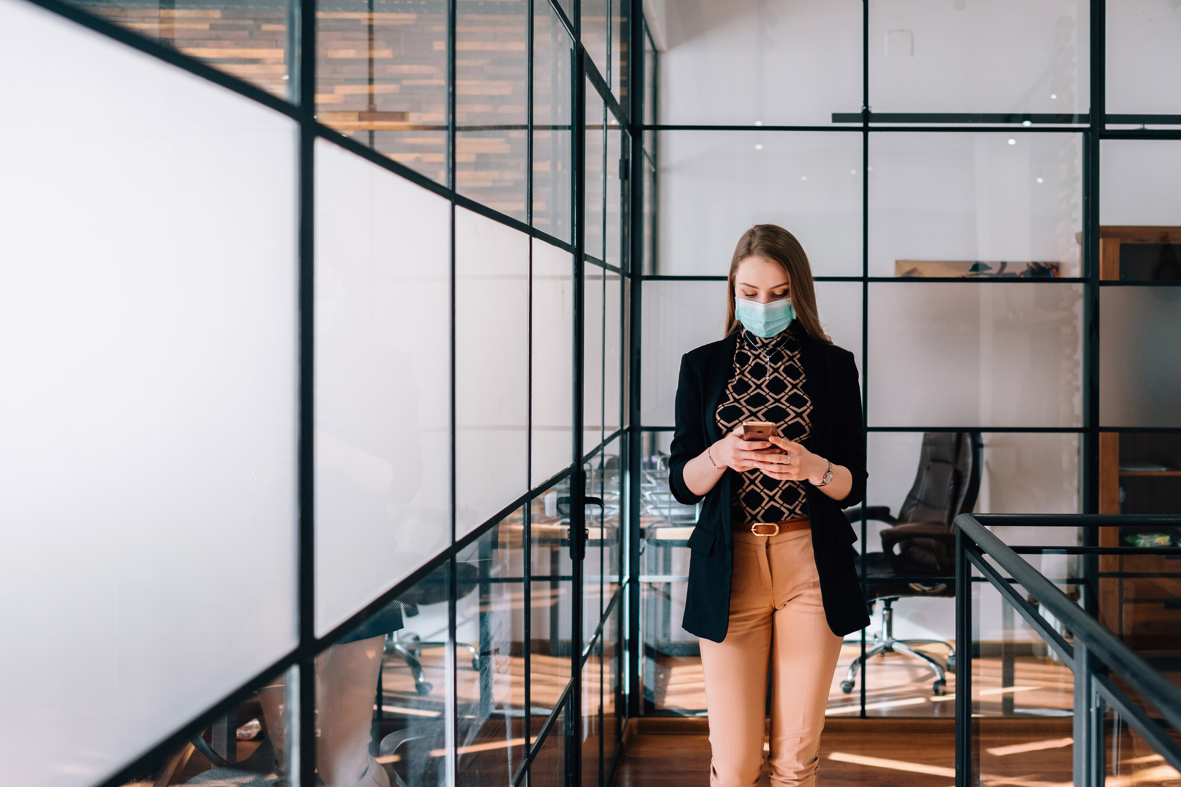 business woman on mobile phone wearing mask in the office