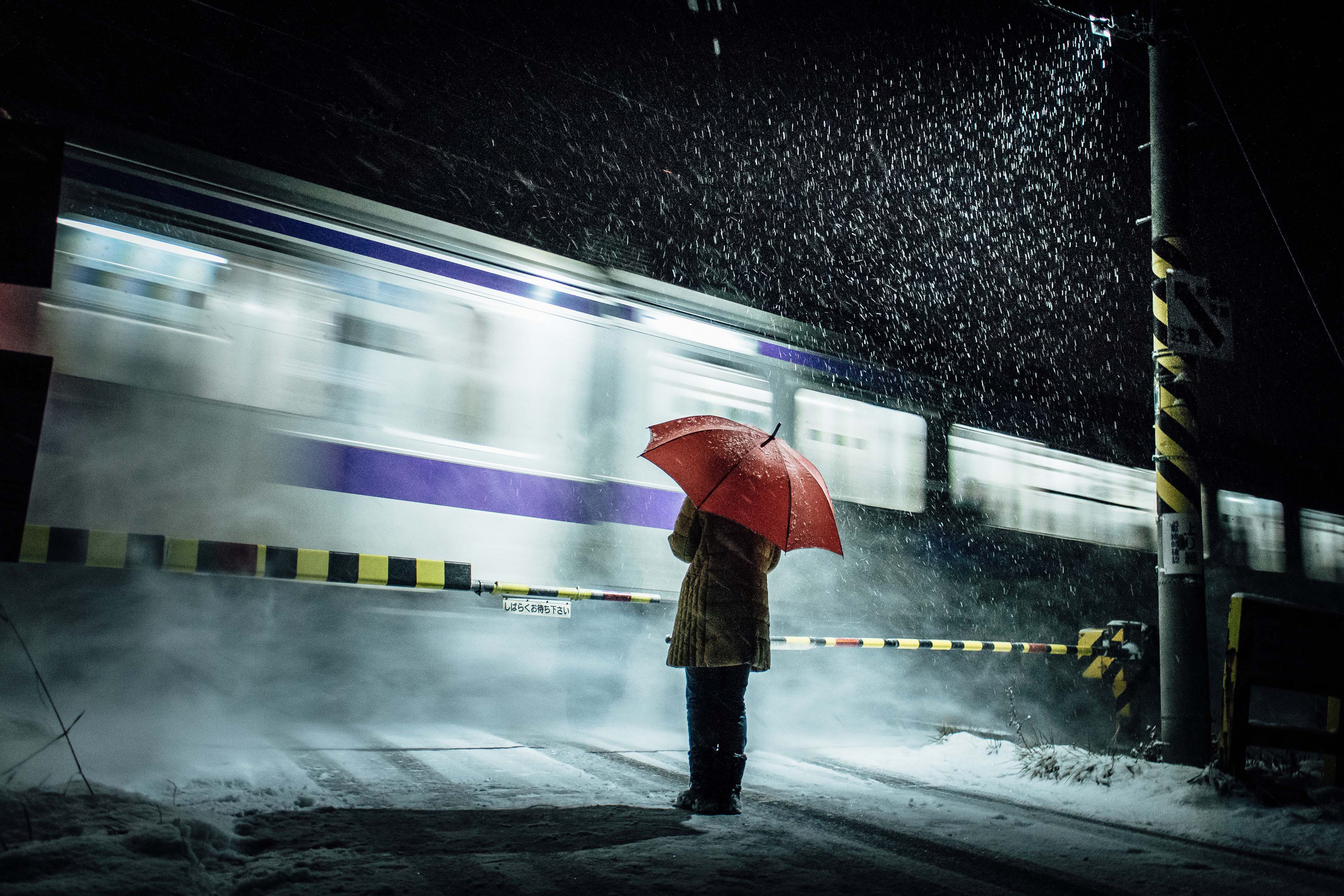 Woman in a snow storm stands at railway crossing