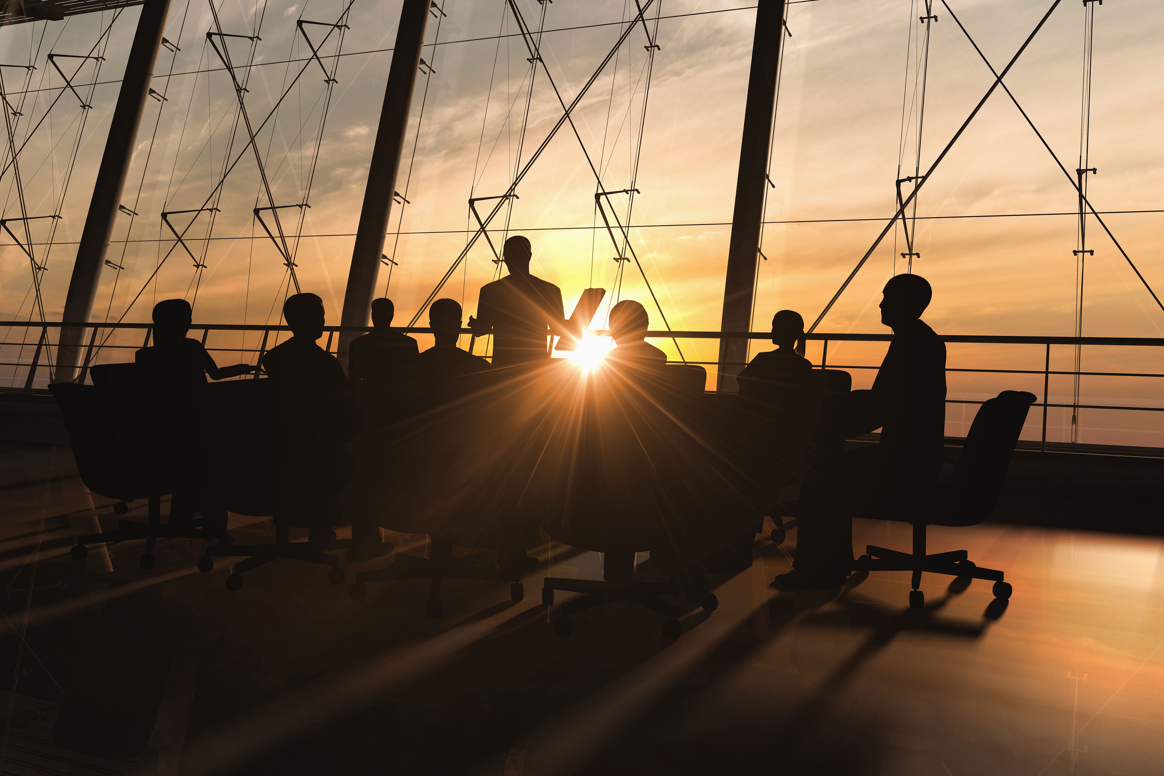 Business team meeting in glass-walled conference room at sunset