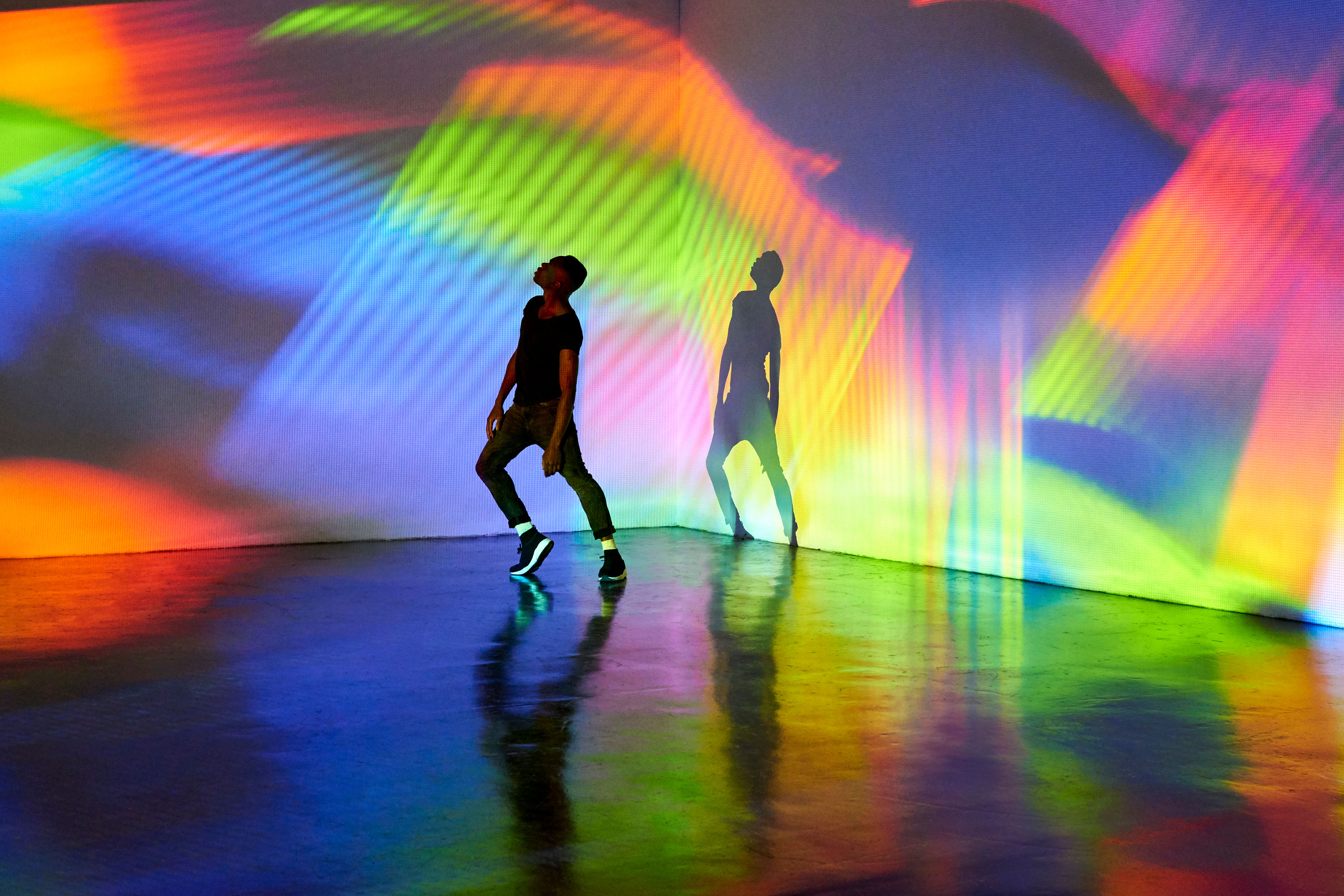 Man dancing in front of large scale abstract image