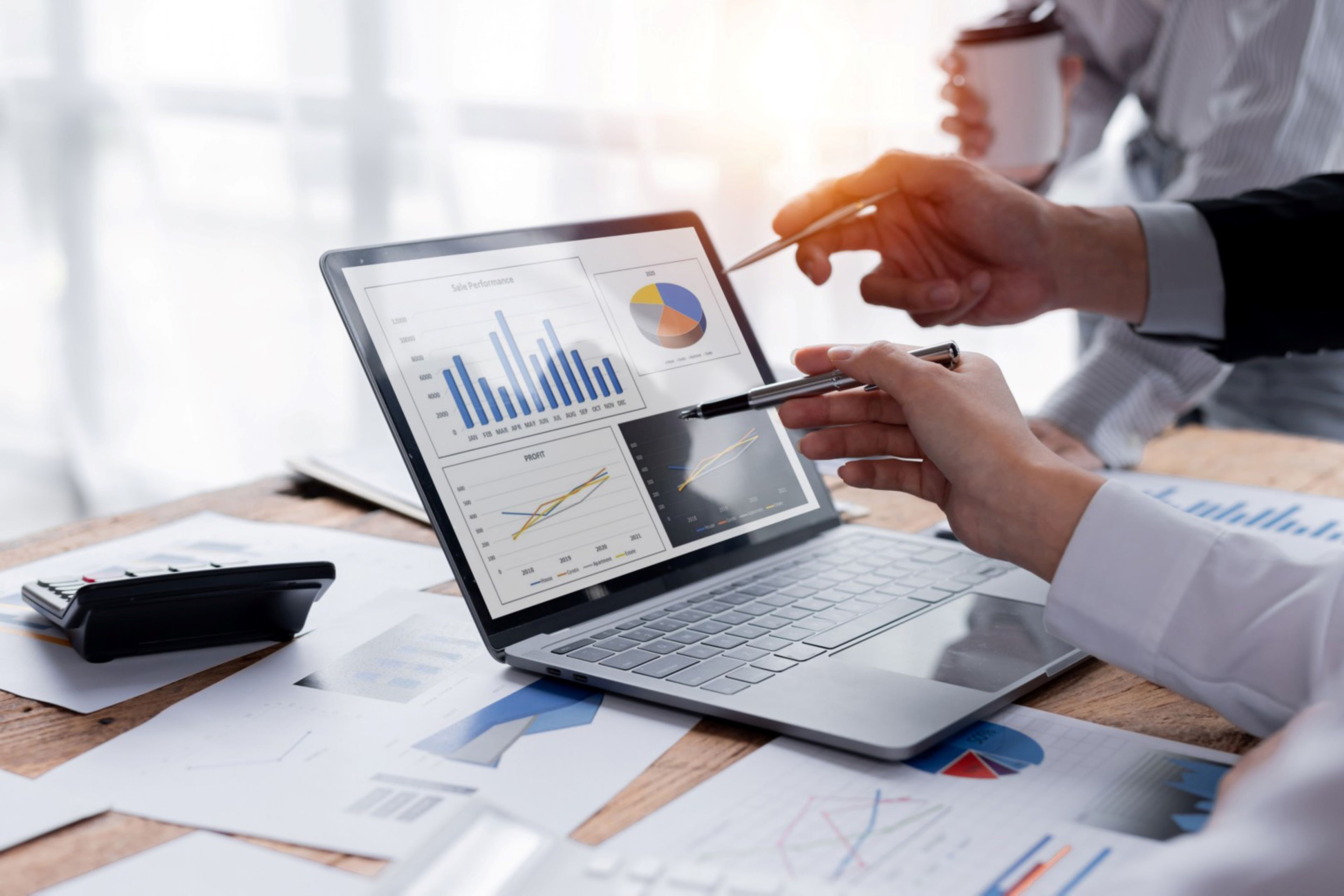 Two business people analyzing financial graph on laptop