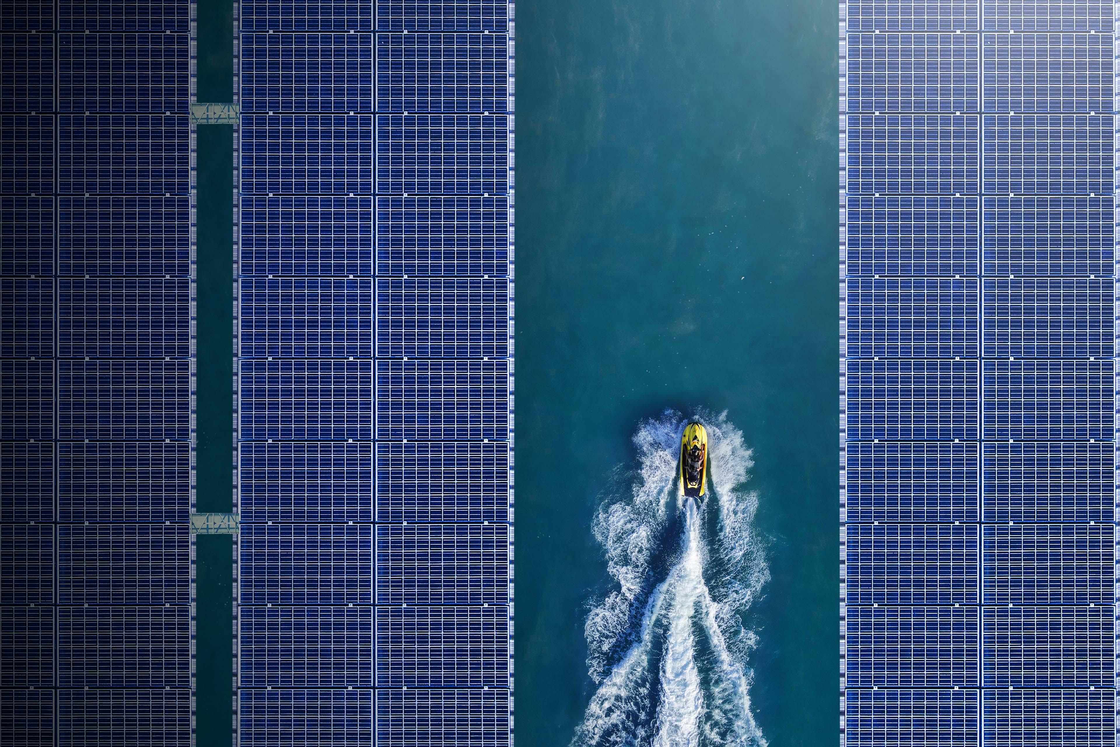 Aerial view of jetski between solar panels floating in a dam background