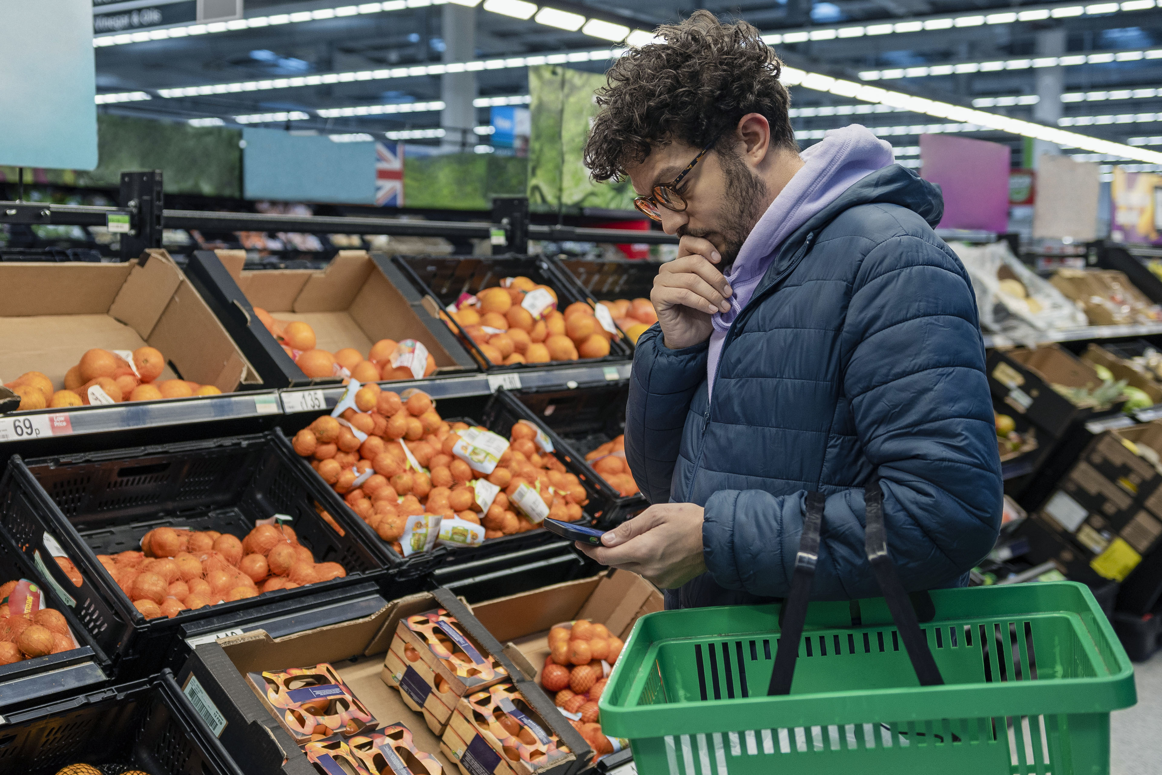 homem pensativo ao fazer compras em um mercado.