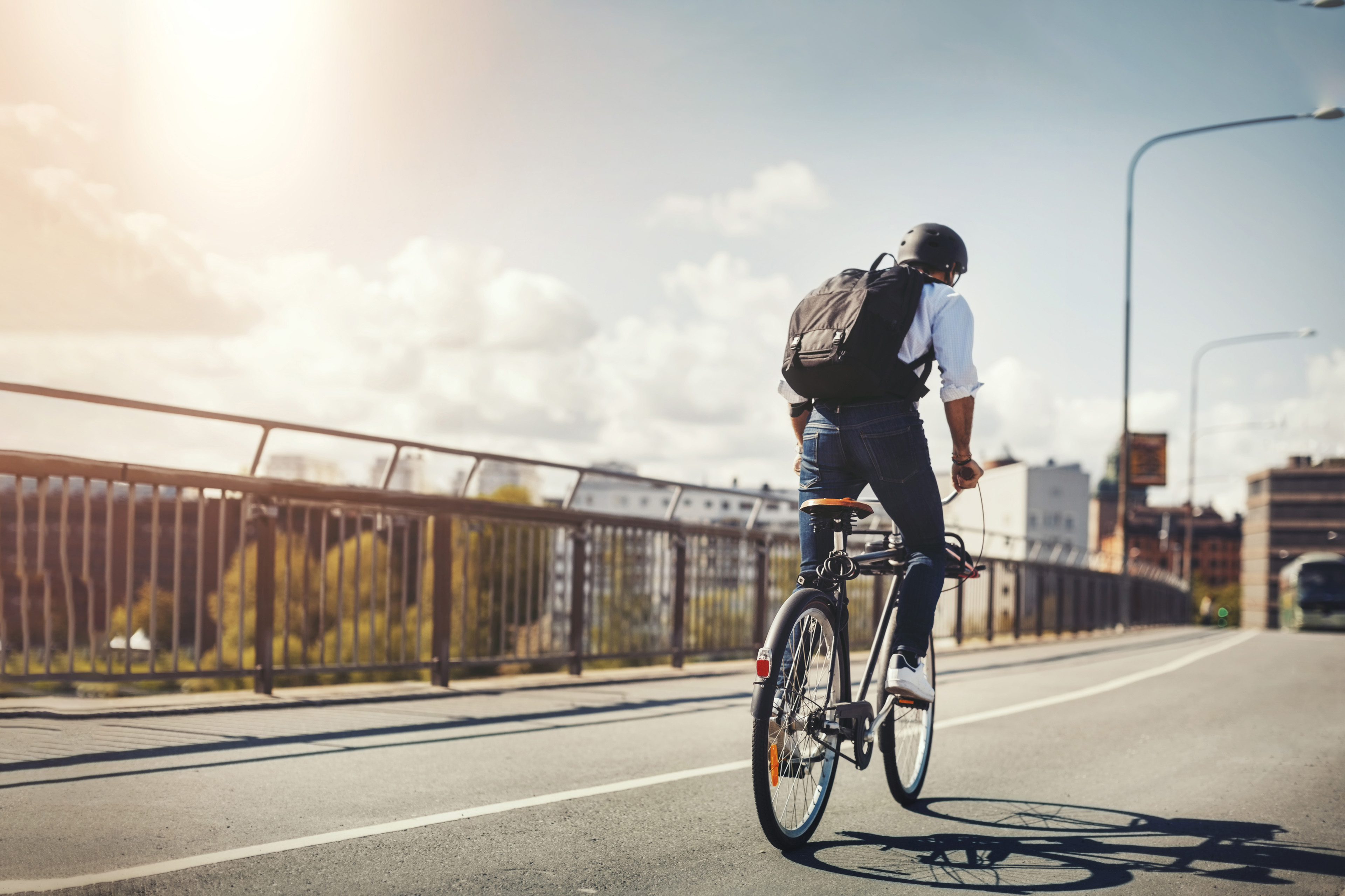  Bakifrån av affärsman som cyklar på bro i staden