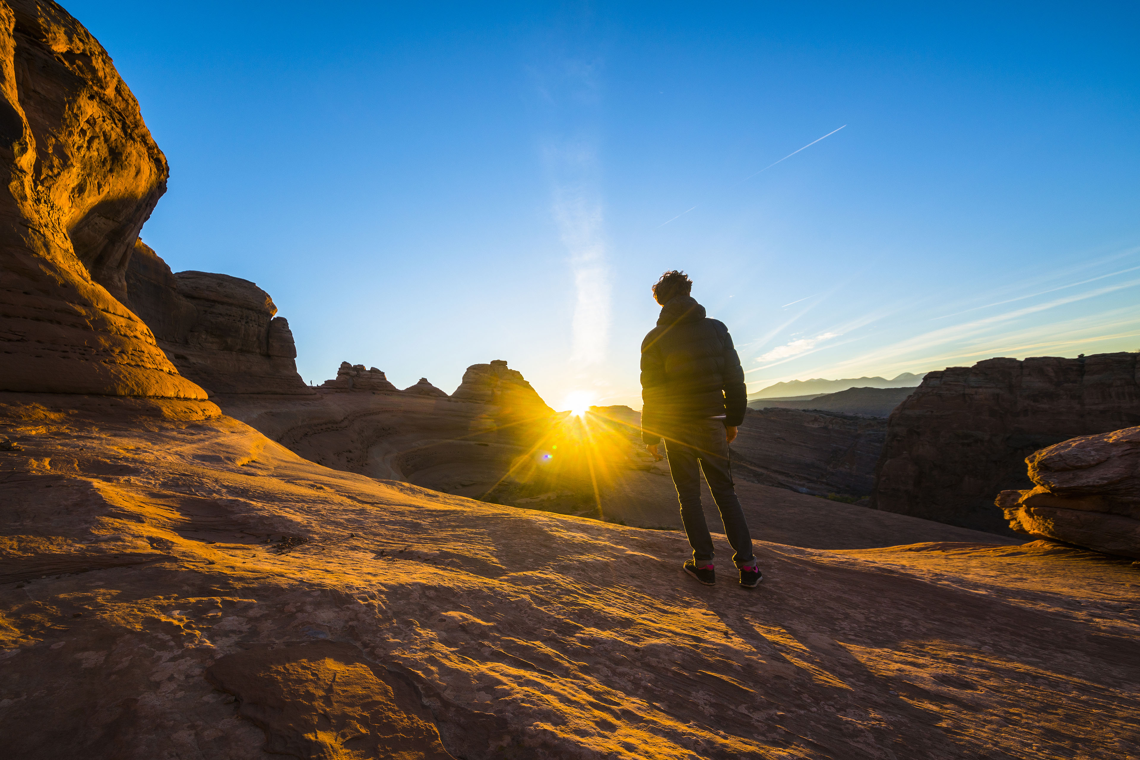 Bild pä Resenär och vandrare som beundrar soluppgången i den röda kanjonen i närheten av Delicate Arch