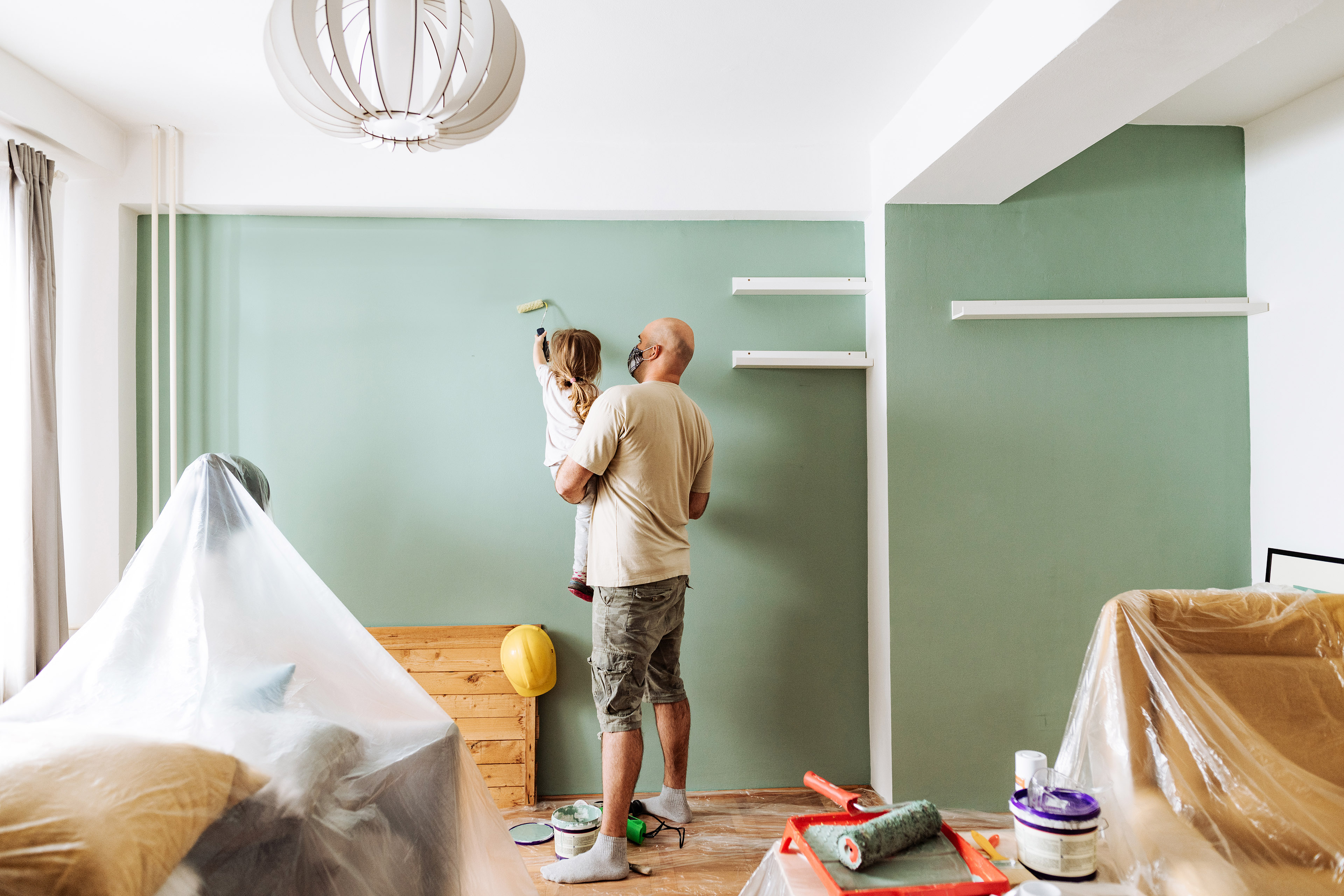 Both father and daughter are painting a wall