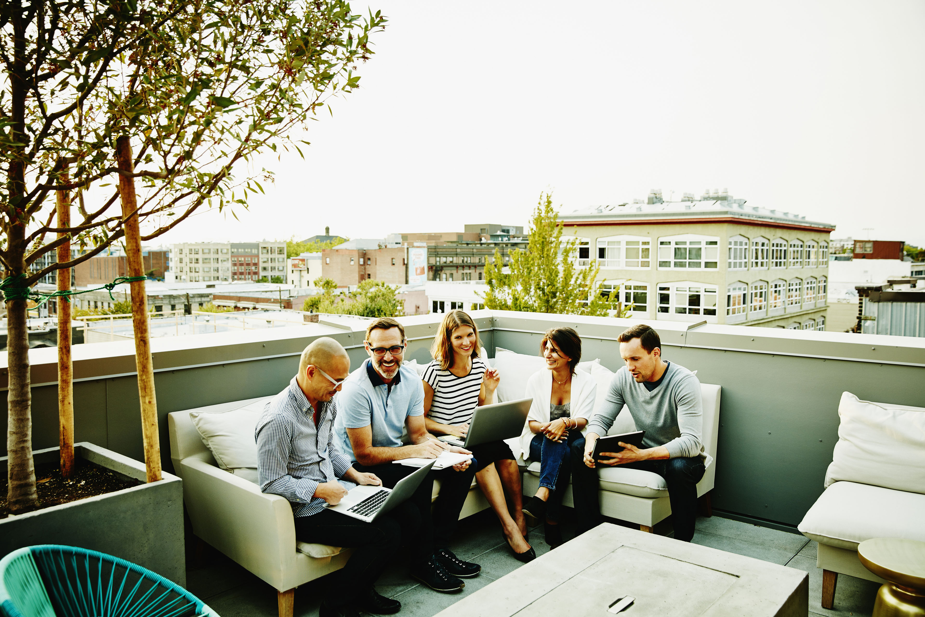 Smiling group of colleagues having informal meeting on terrace of office building