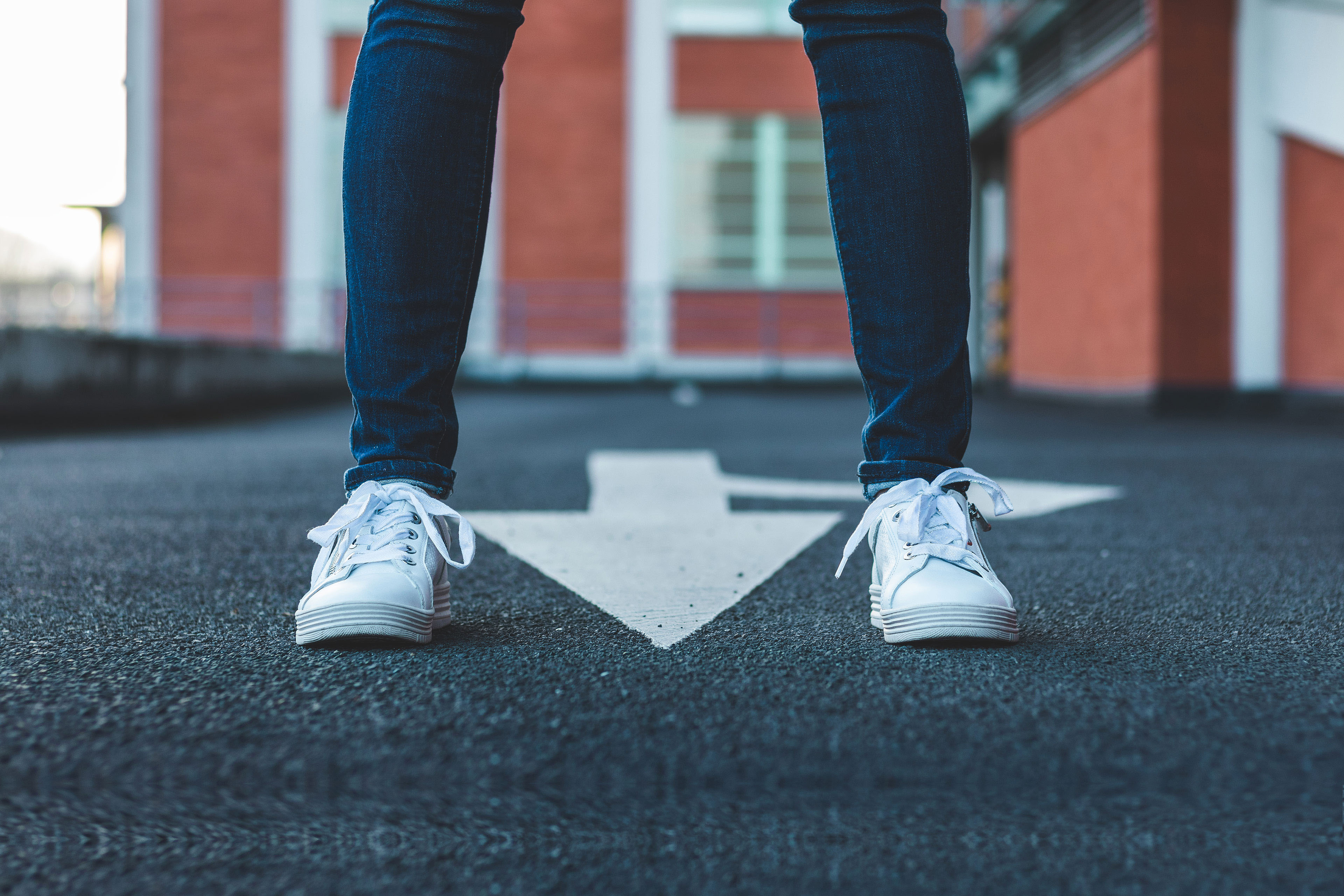 woman standing on asphalt road with directional sign