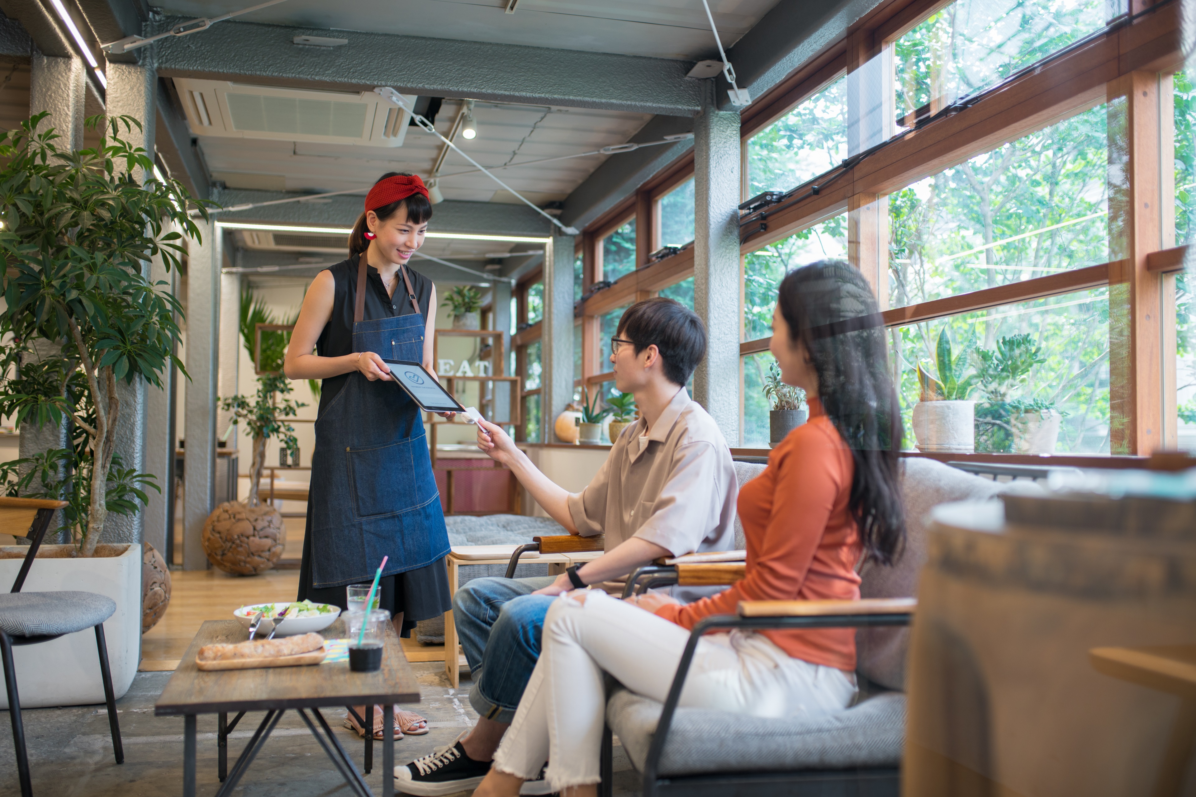 一對年輕男女在咖啡廳用餐後使用非接觸式支付結帳。